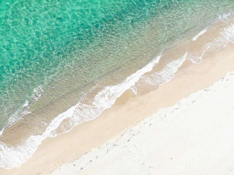 aerial view of waves on a white-sand beach